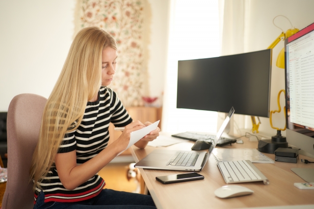 ノートPCとデスクトップPCの前の女性