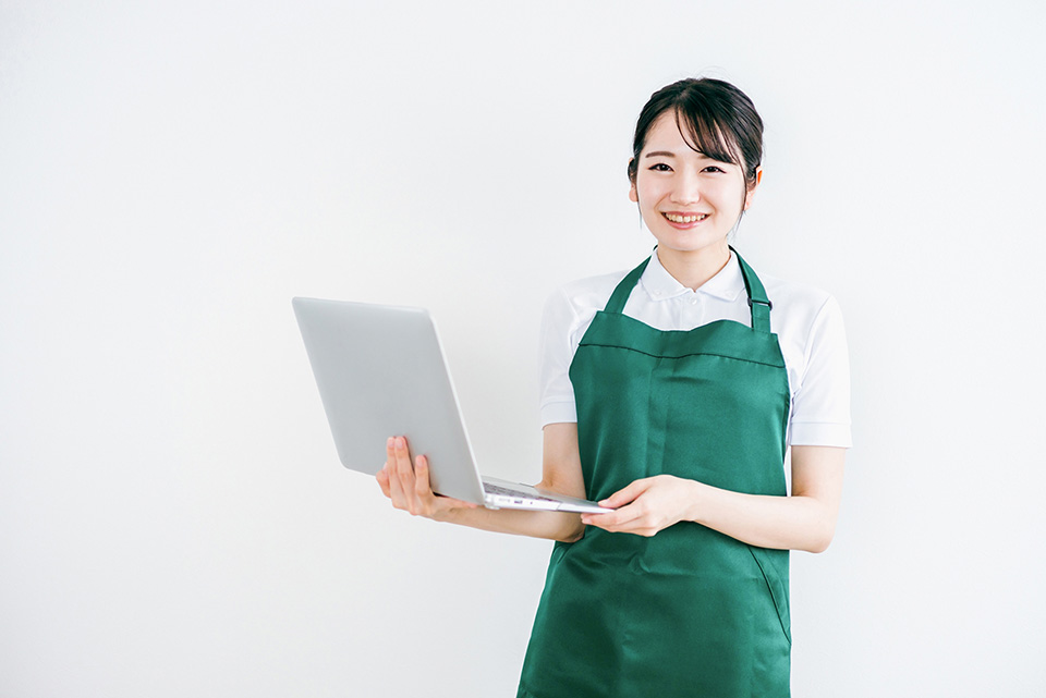 パソコンを持つエプロンの女性