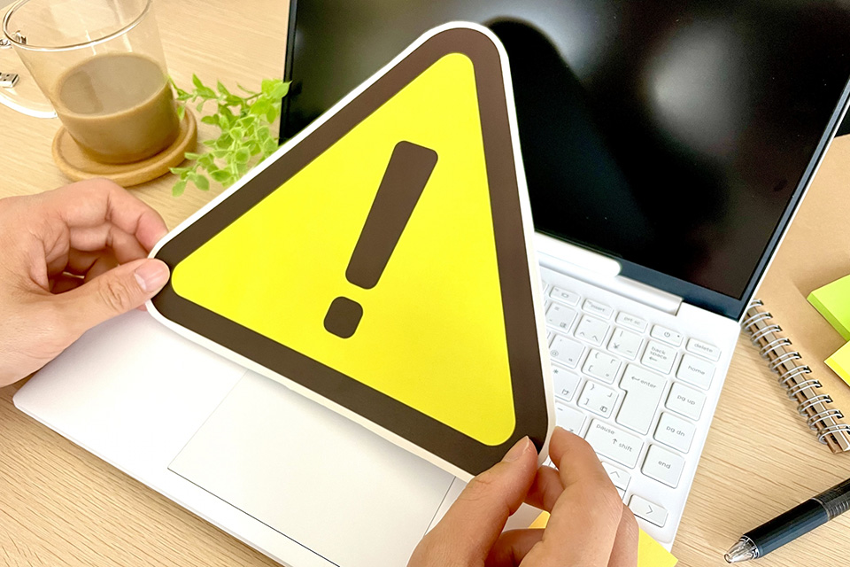 パソコンの前で警告のマークを持つ人