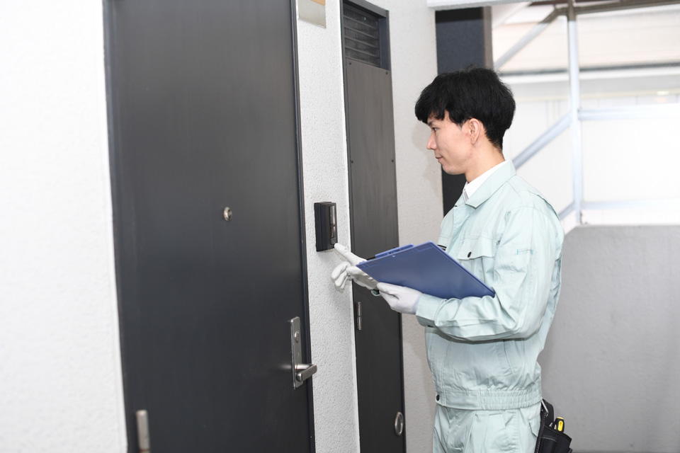 インターホンを押す作業服の男性