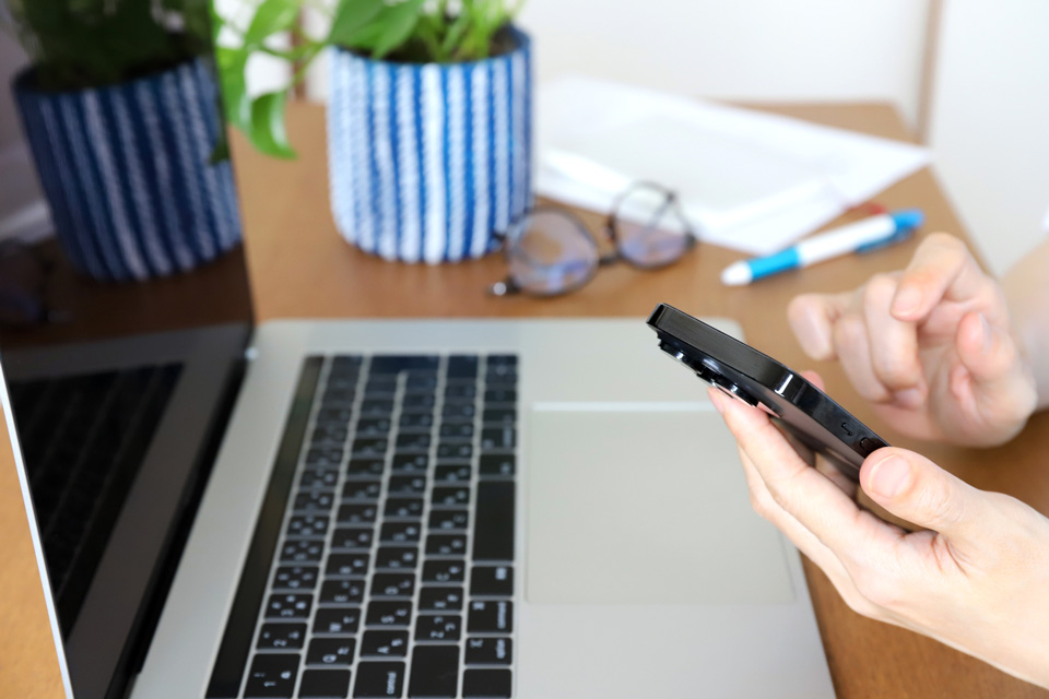 ノートパソコンの前でスマホを使う人